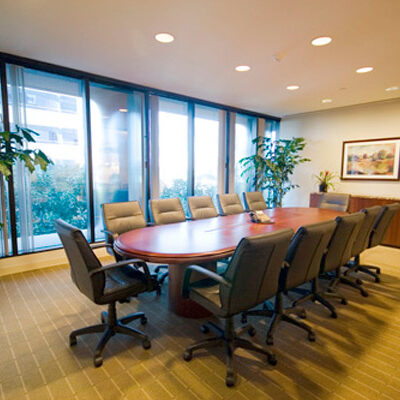 Glass-clad office building with landscaped green lawn and palm trees in the foreground.