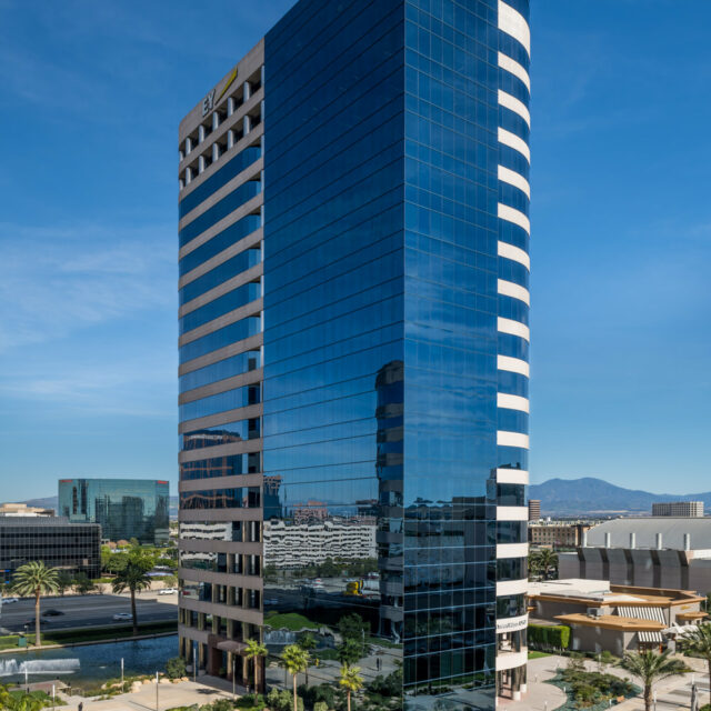 Executive boardroom with large oval conference table, leather chairs, and floor-to-ceiling windows.