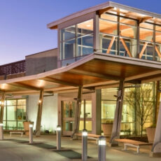 Exterior view of the Fullerton Community Center entrance with modern glass and wood architectural details illuminated at dusk.