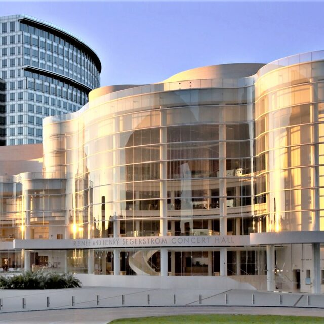 The Segerstrom Concert Hall reflecting golden light at sunset, showcasing its modern glass-and-steel design.