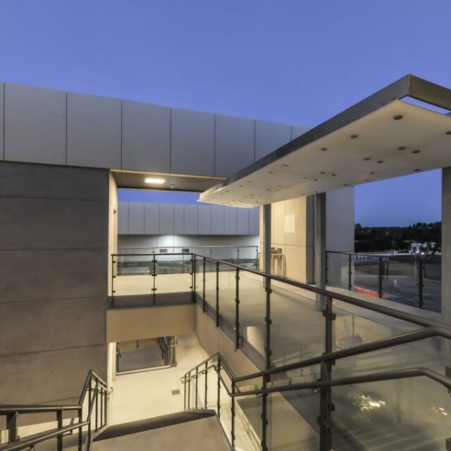 High school campus architecture with glass balustrades and evening lighting