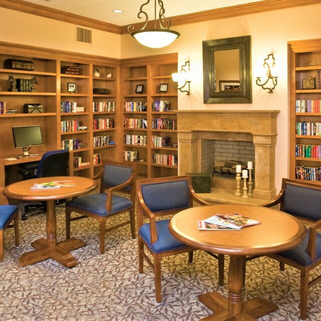 Library and reading room with bookshelves, fireplace, and computer desk