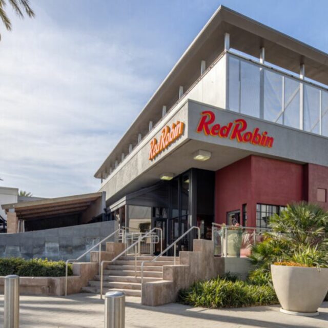 Exterior of Red Robin restaurant with bold signage, stairway entrance, and landscaped planters.