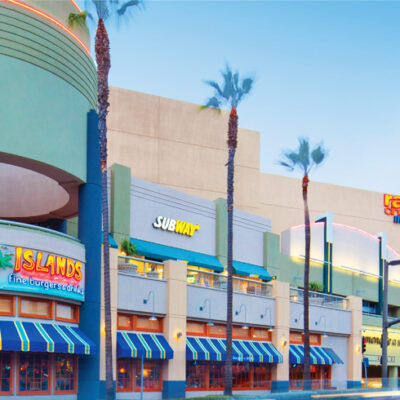 Exterior view of retail storefronts with colorful signage including Subway and Islands restaurant.