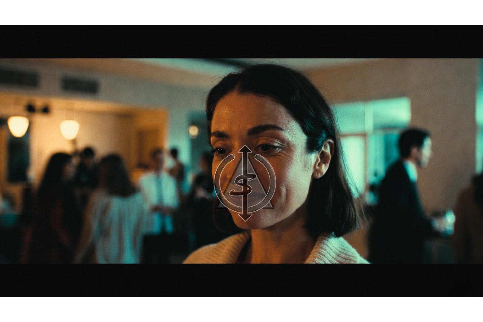 Person standing calmly in a softly lit room with others blurred in the background, symbolizing quiet confidence without comparison.