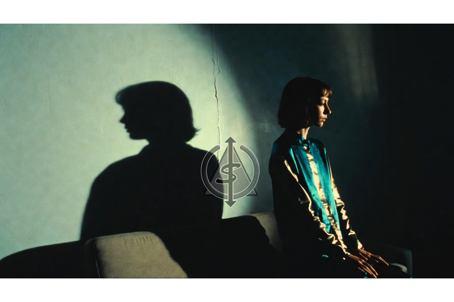 Person rising from a seated position while their shadow remains hunched on the wall behind them, symbolizing letting go of a stuck victim identity and stepping into personal power.