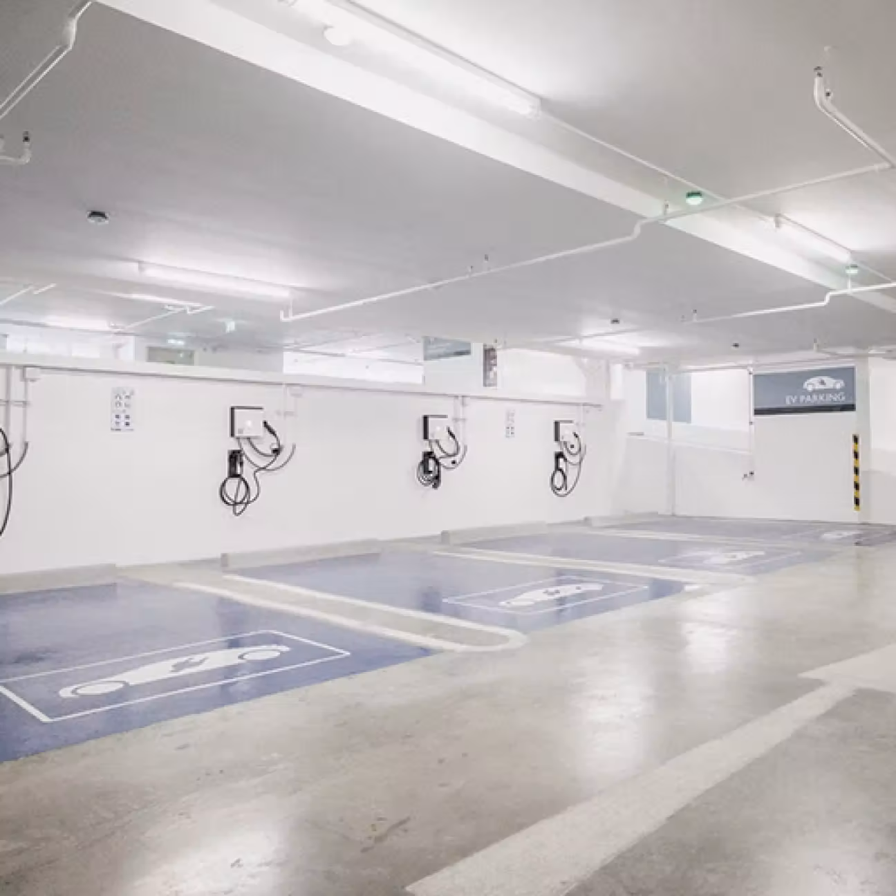 Indoor parking spaces designated for electric vehicles with charging stations mounted on the wall.
