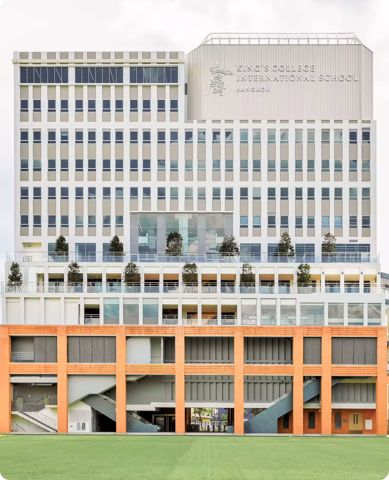 Modern multi-story building with King's College International School Bangkok sign and a green lawn in front.