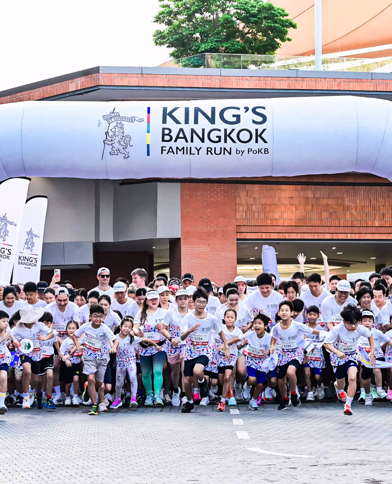 Group of runners, including children and adults, starting the King’s Bangkok Family Run event.
