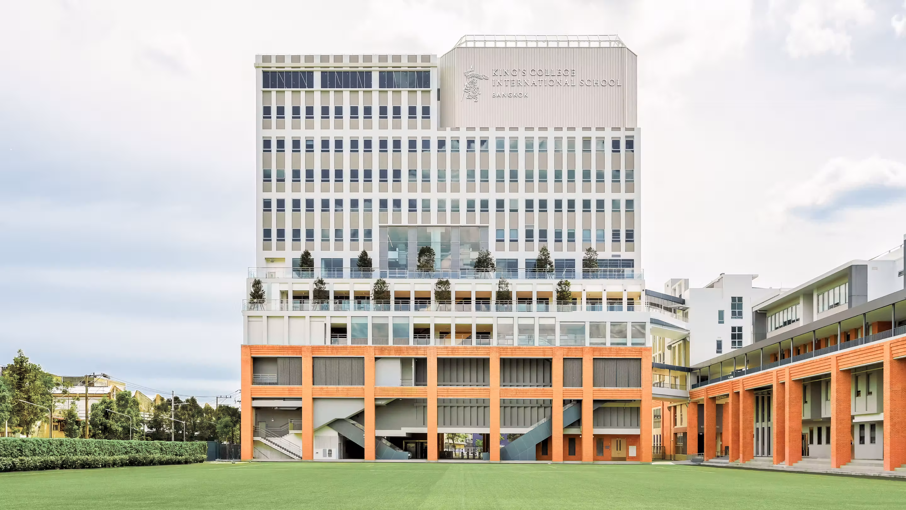 Front view of King’s College International School Bangkok with green field in the foreground.