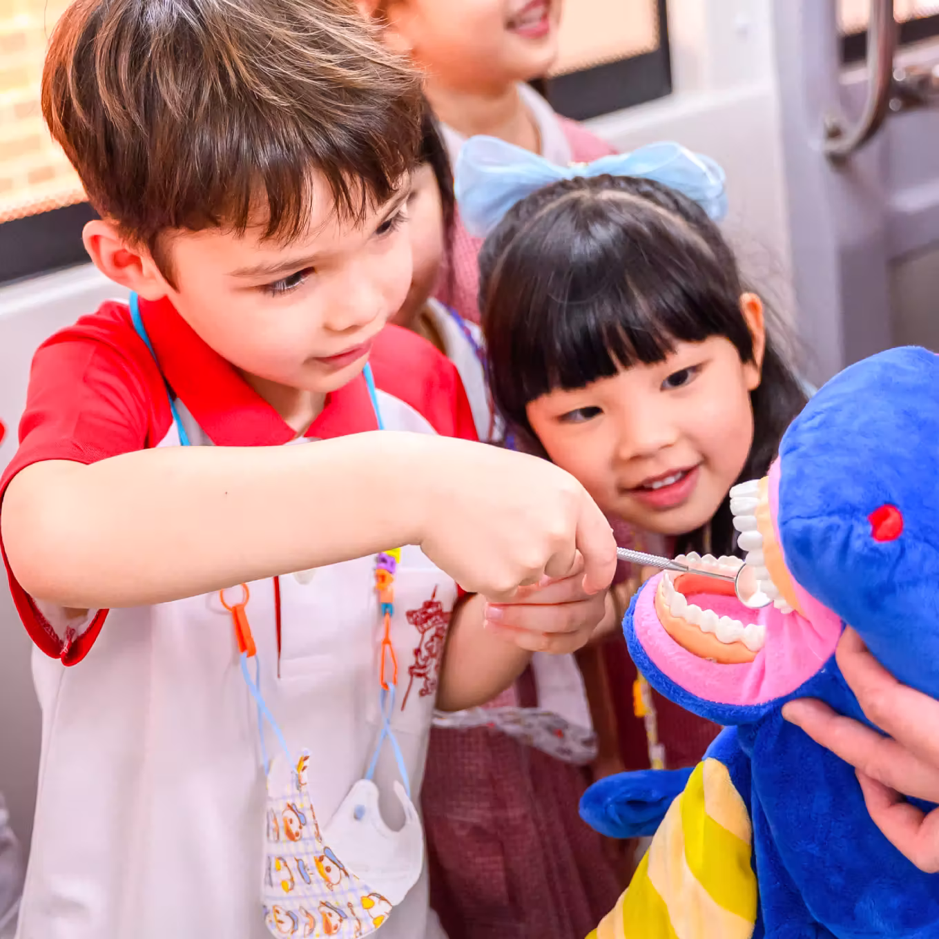 Young children examining dental model teeth with a dental mirror during a learning activity.