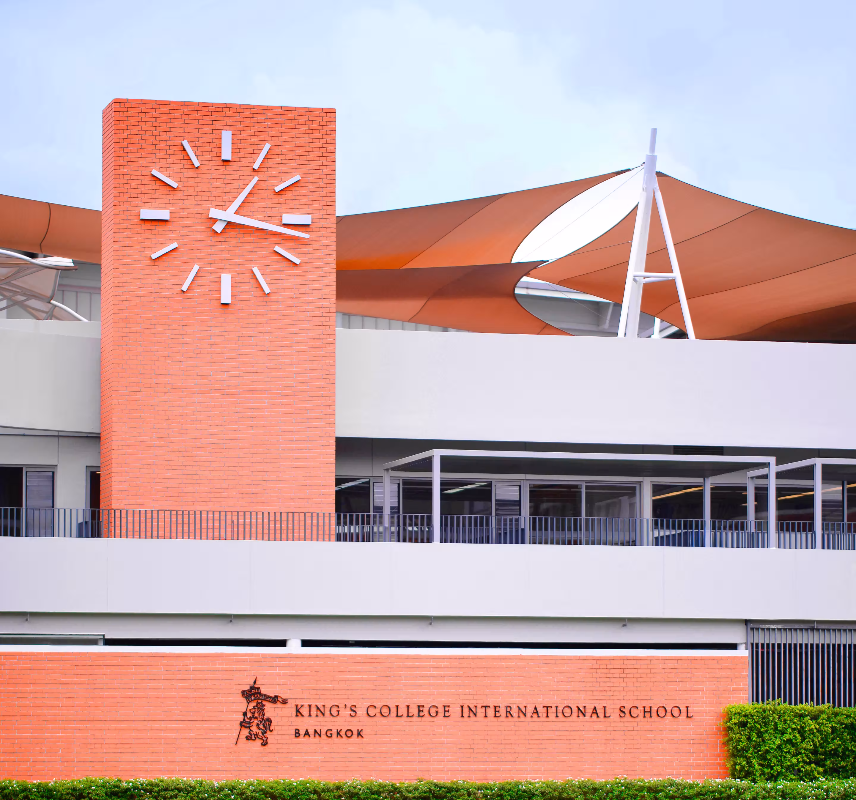 King's College International School Bangkok building with a large clock showing 1:15 on a brick tower.