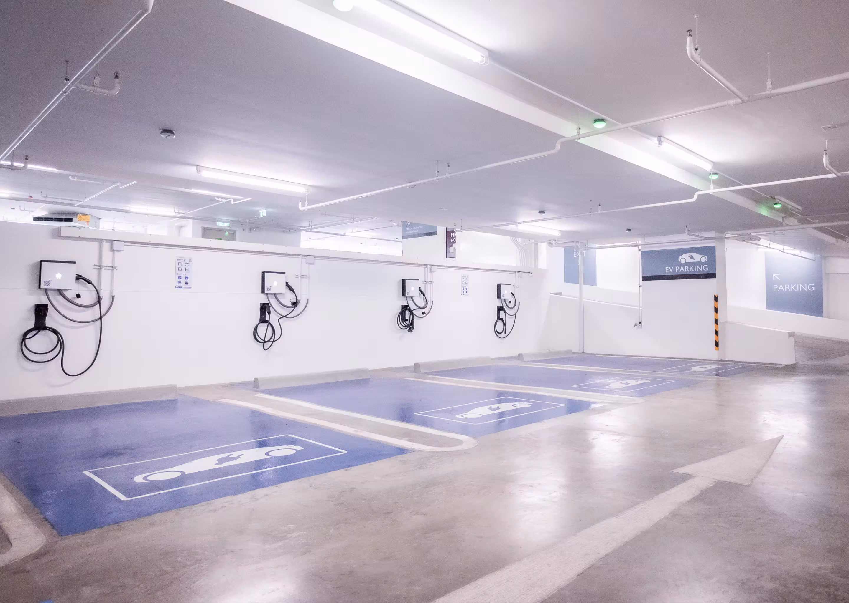 Indoor parking spaces with electric vehicle charging stations marked in blue.