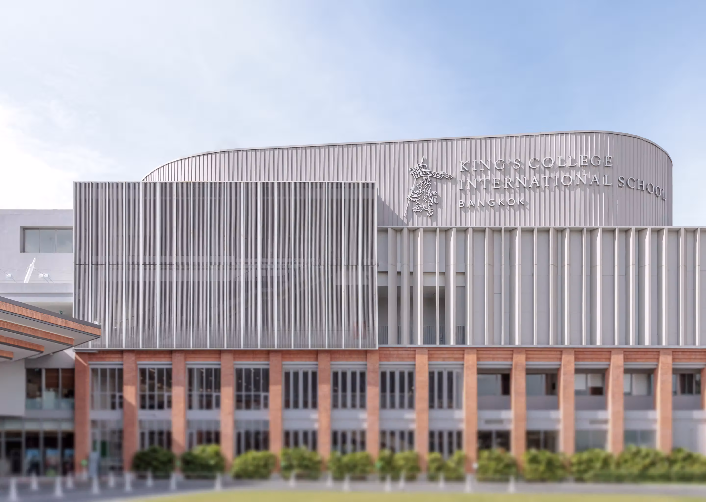 Modern building of King's College International School Bangkok with a large sign and emblem on the facade.