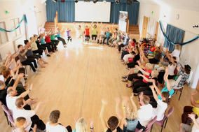 People sitting on chairs in a circle doing mild exercises to music