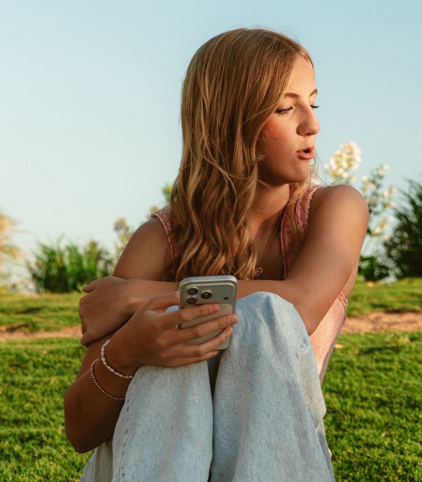 Teen girl sitting on the grass holding her phone