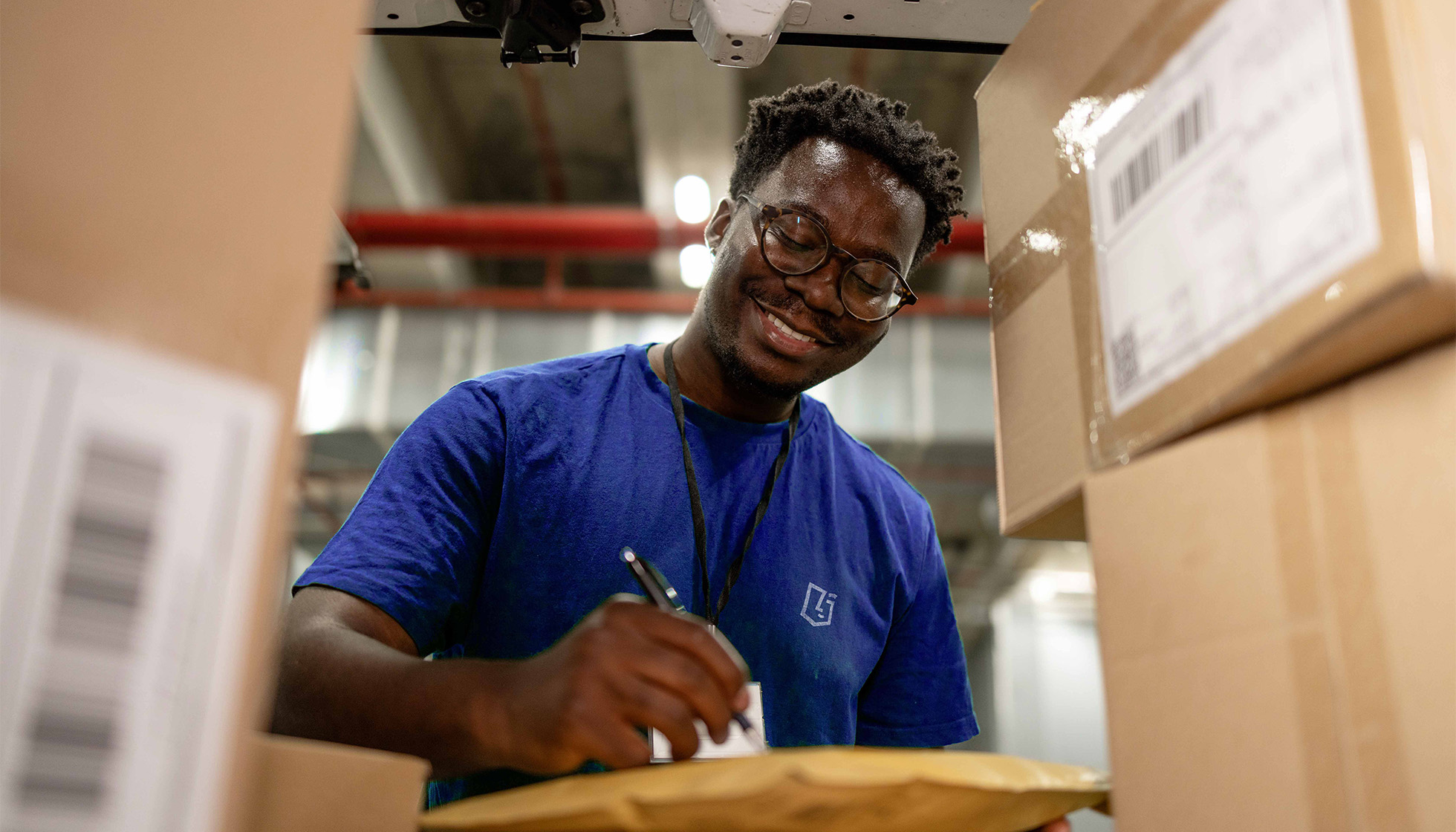 Employé logistique souriant remplissant un bon de livraison dans un entrepôt, illustrant la gestion et l’expédition des produits distribués par VerZ