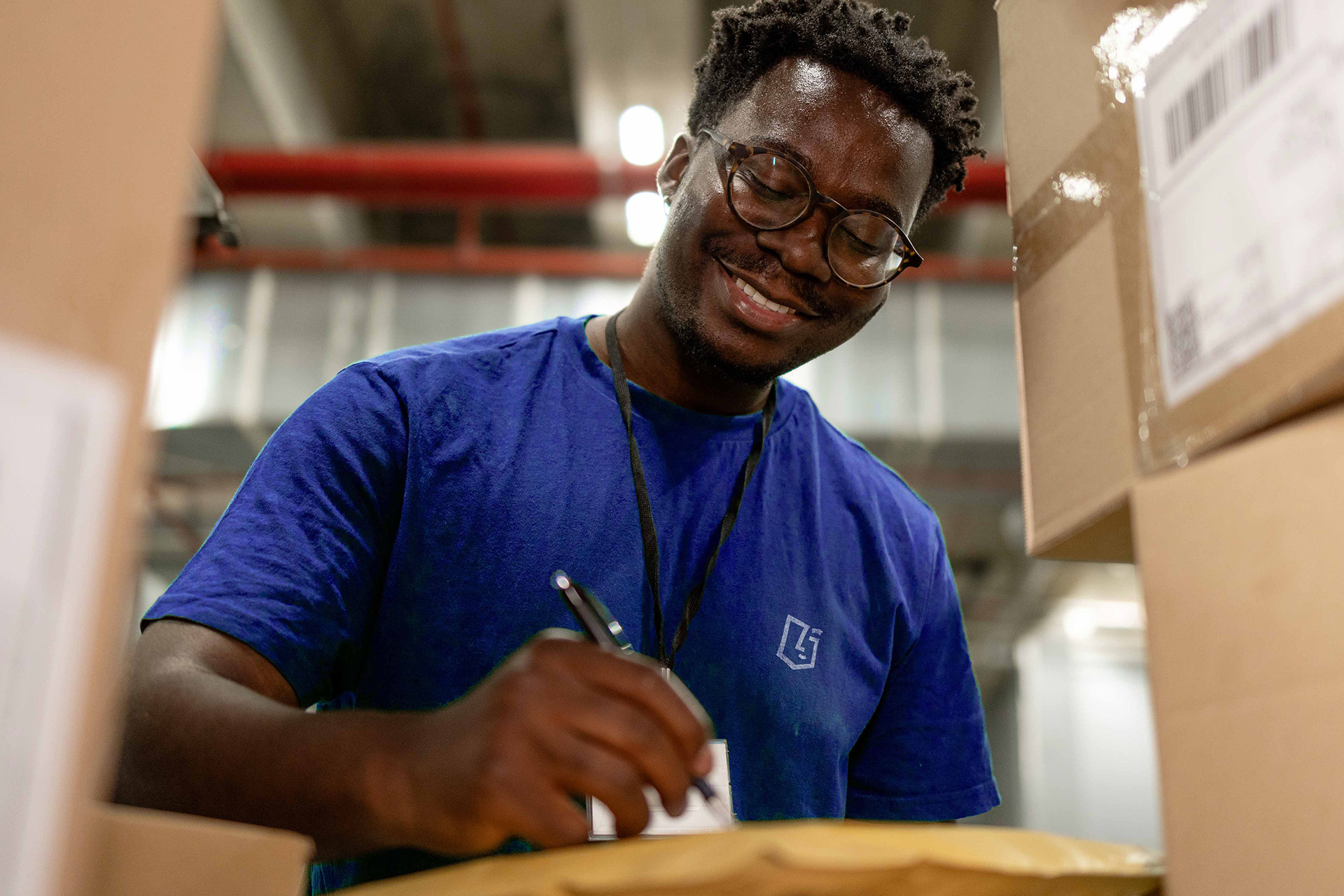 Employé logistique souriant remplissant un bon de livraison dans un entrepôt, illustrant la gestion et l’expédition des produits distribués par VerZ