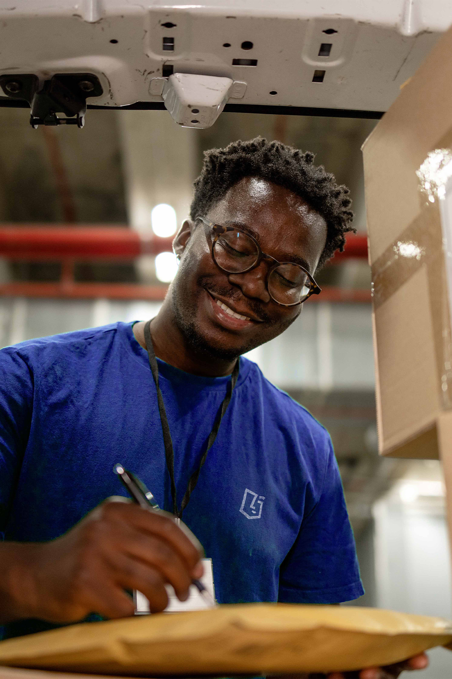 Employé logistique souriant remplissant un bon de livraison dans un entrepôt, illustrant la gestion et l’expédition des produits distribués par VerZ