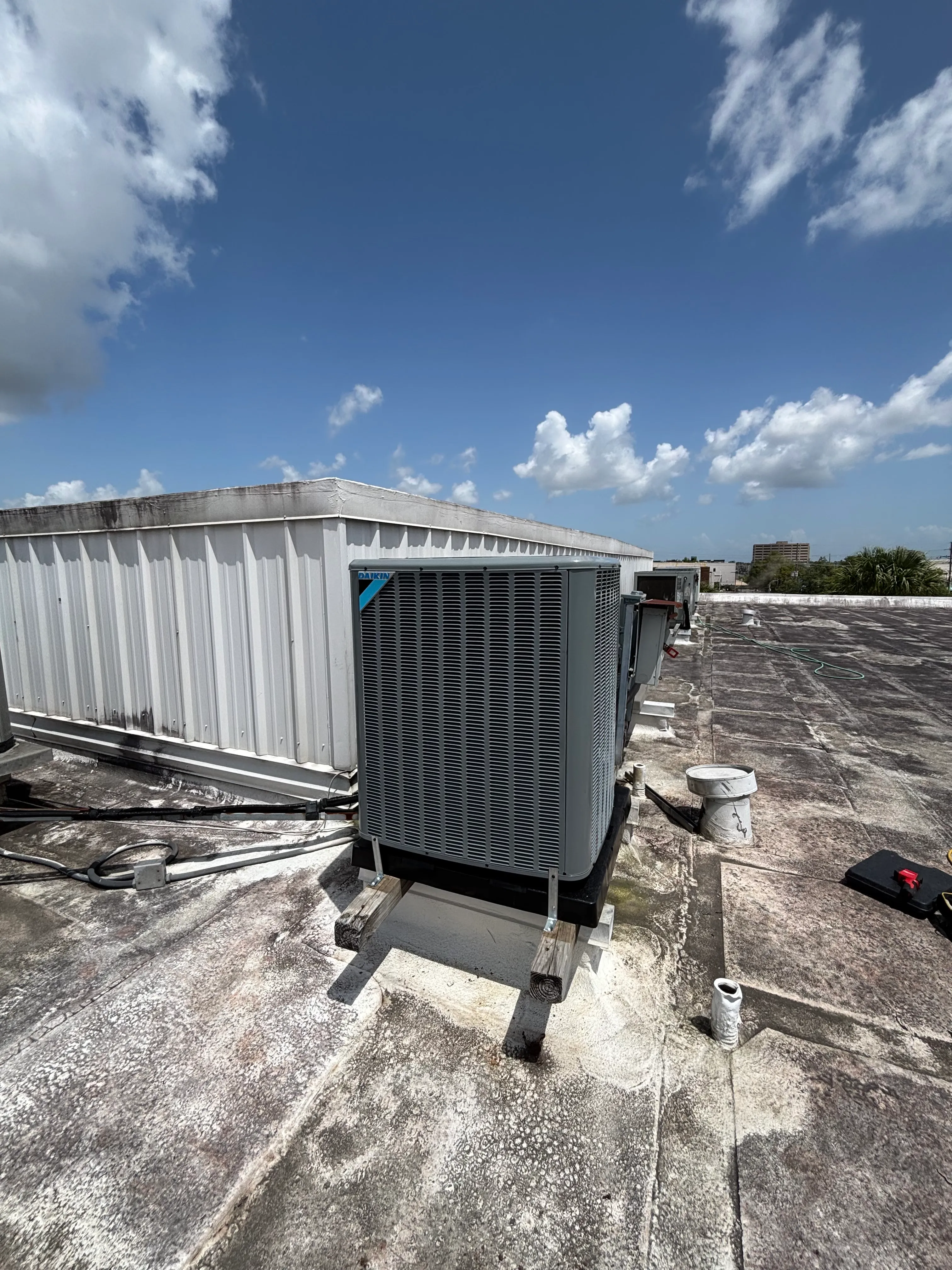 Rooftop air conditioning units under a blue sky with scattered clouds.