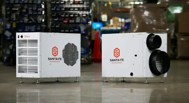 Two white Santa Fe dehumidifiers with orange logos placed on a warehouse floor.
