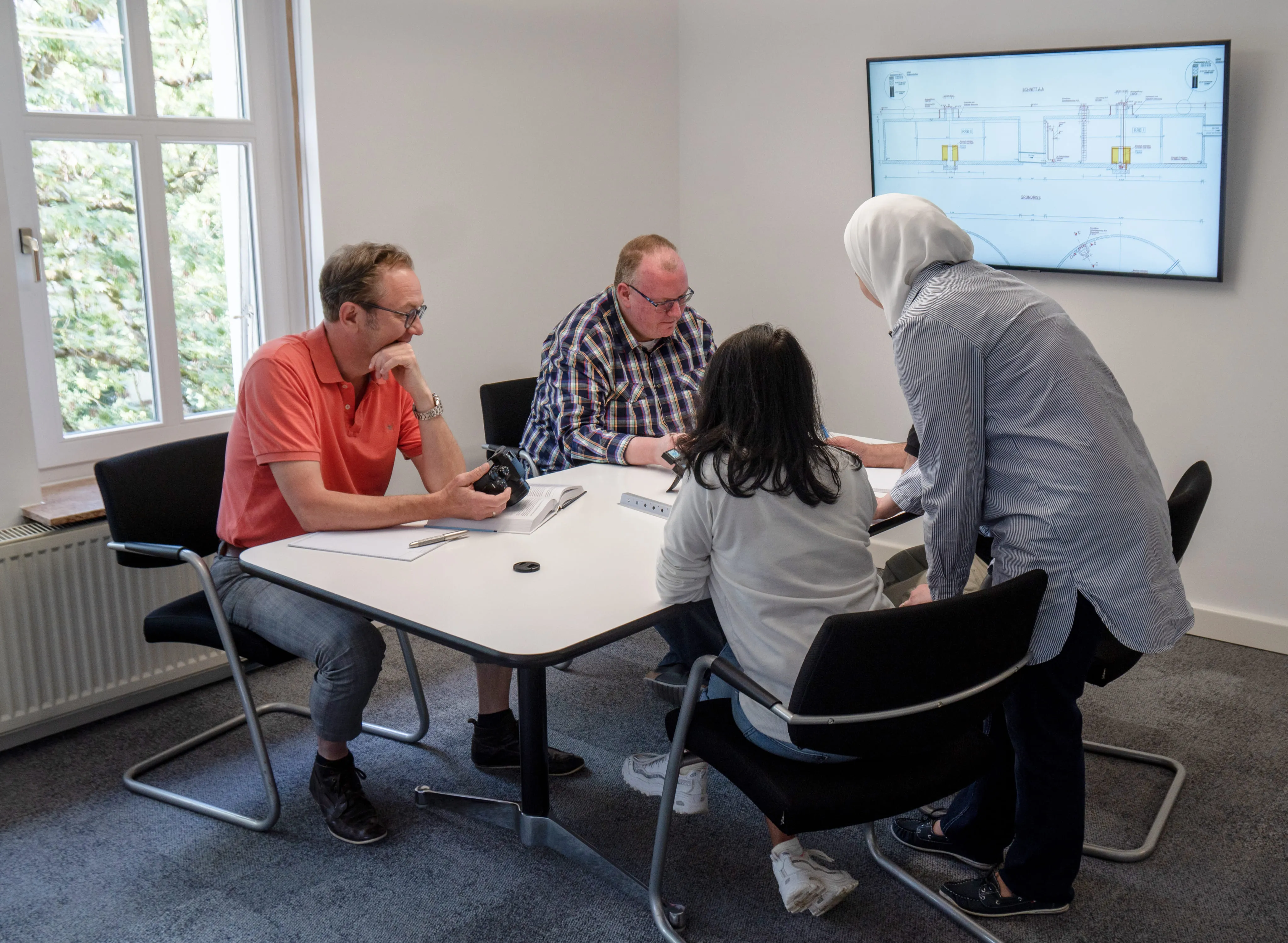 Teammeeting mit Bauplänen – interdisziplinäre Planung und Projektbesprechung im Ingenieurbüro