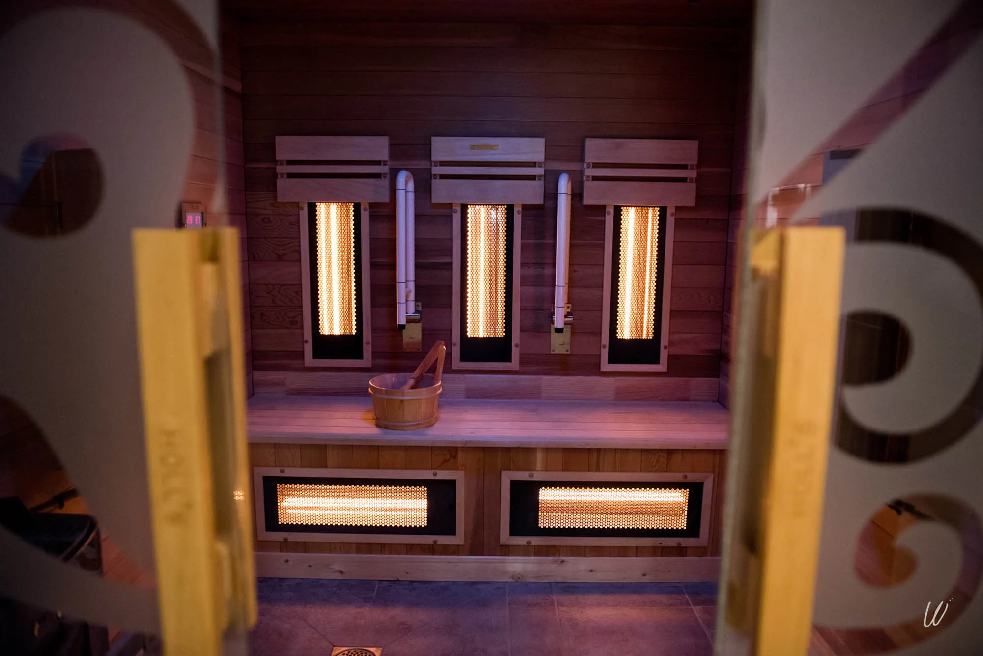 Vue intérieure d’un sauna infrarouge à l’hôtel Armes de Champagne, avec banc en bois et seau traditionnel