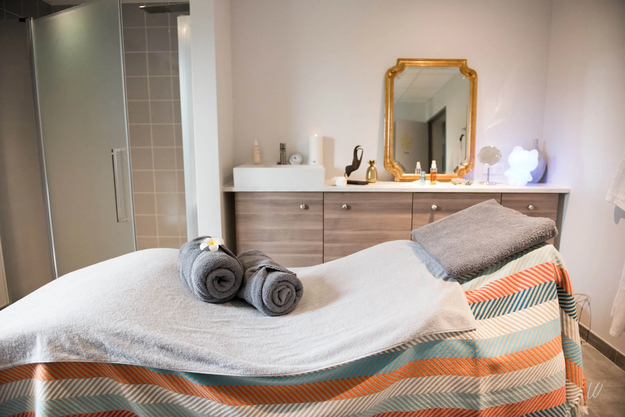 Cabine de soins du spa à l’hôtel Aux Armes de Champagne, avec table de massage, serviettes roulées et ambiance zen