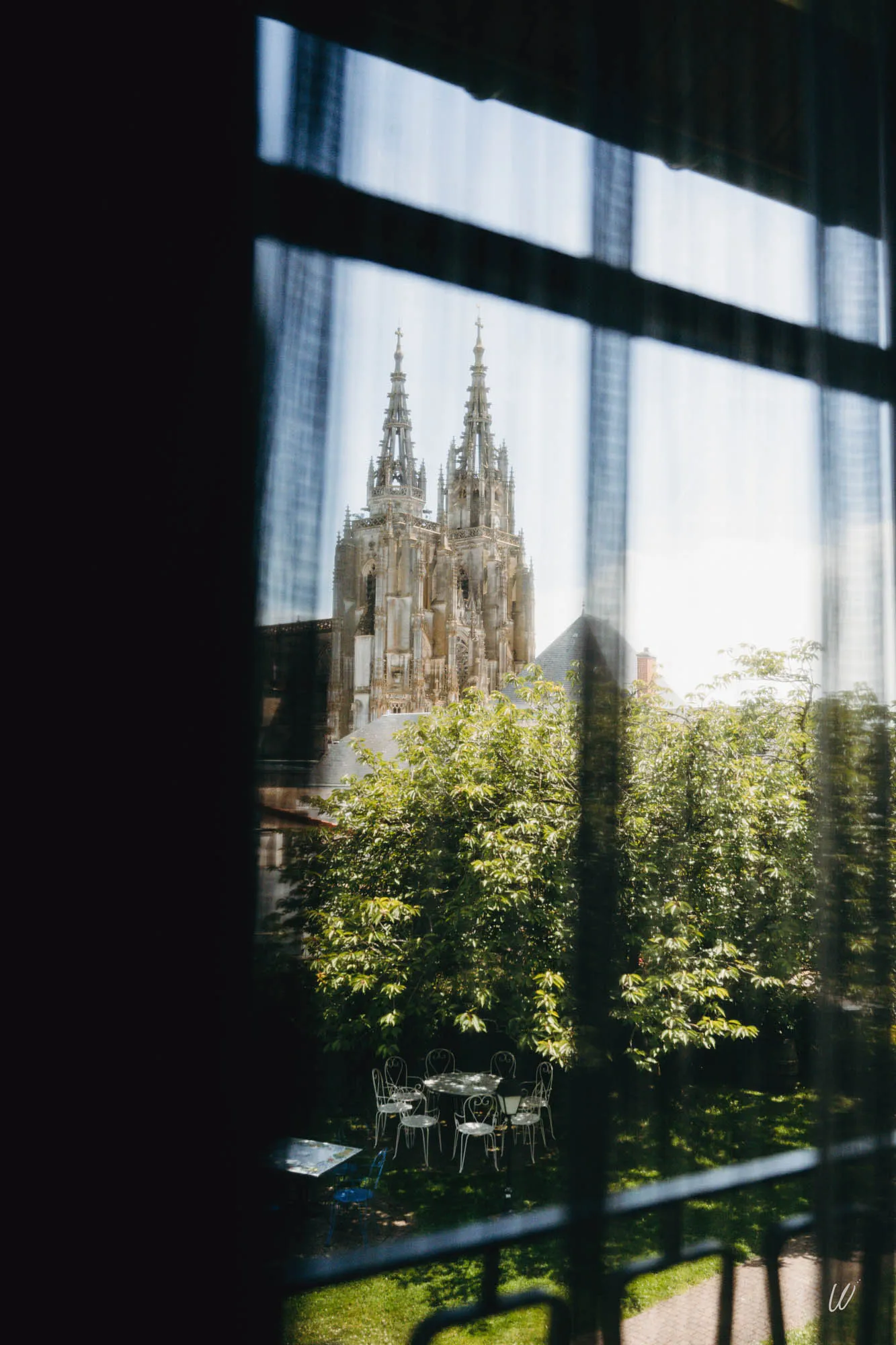 Vue depuis une chambre de l’hôtel Armes de Champagne sur la basilique Notre-Dame de l'Épine, à travers un voilage.