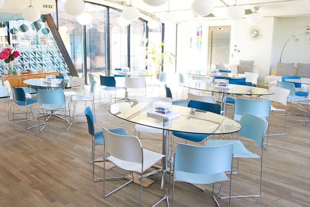 Big room with blue and white chairs. There are white lantern lights hanging down from the ceiling.