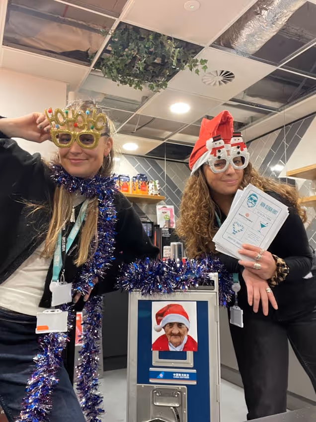 two members of the Runway East Bristol team with festive glasses on with cards in their hands to hand out to members
