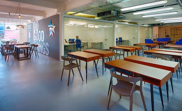 An image of co-working space with desks and meeting room with glass walls.