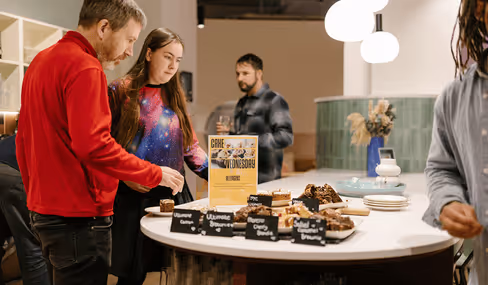 People gathered around table with assorted baked goods and coffee at Runway East Birmingham