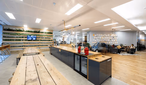 Modern, open-plan office kitchen with wooden tables and shelving