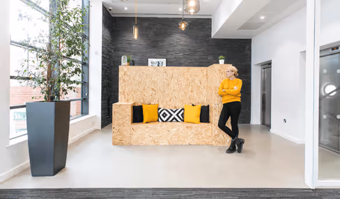 Runway East Bristol Bridge office reception area with yellow cushions and wood-textured seat, with person standing