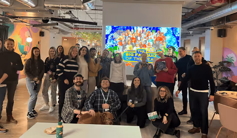 Group photo of team members in office with colorful art wall backdrop