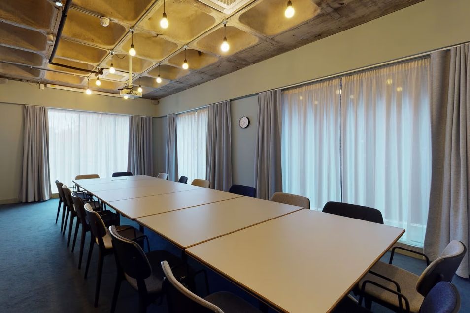 Modern conference room with long table, hanging lights, and soft curtained windows