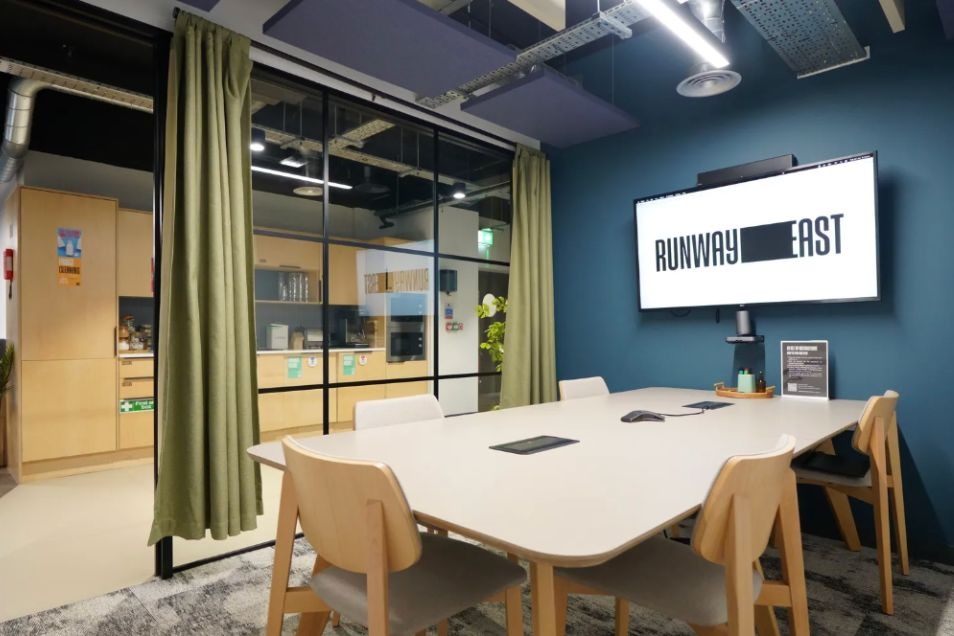 Runway East London Bridge meeting room with white table, wooden chairs, and large screen