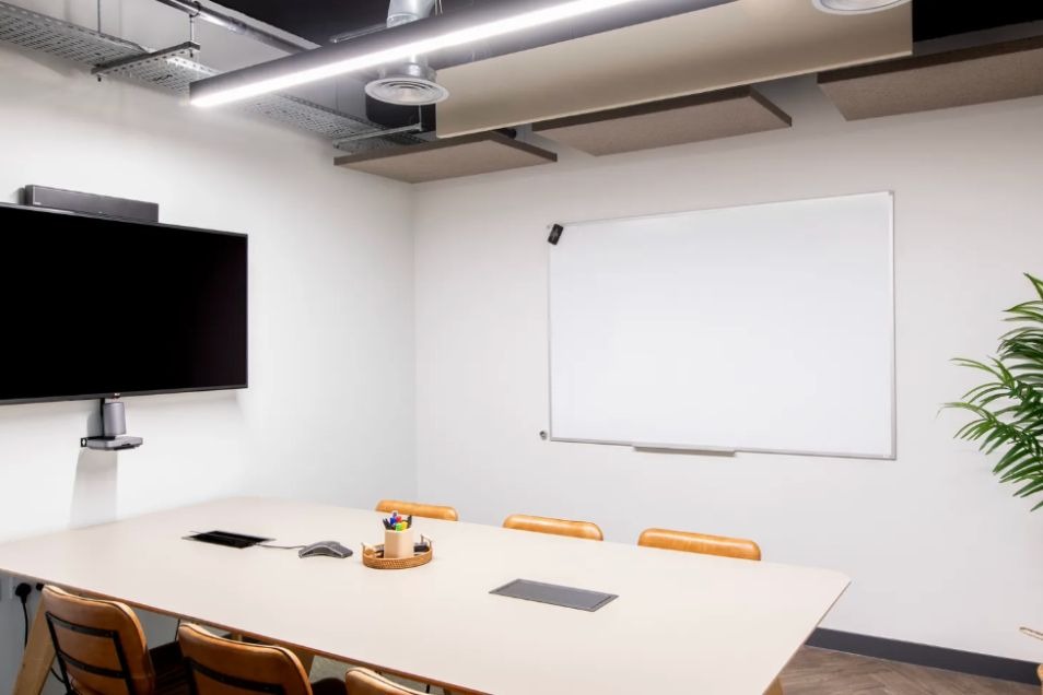 Runway East Borough Market meeting room with white table, TV, whiteboard, and orange chairs