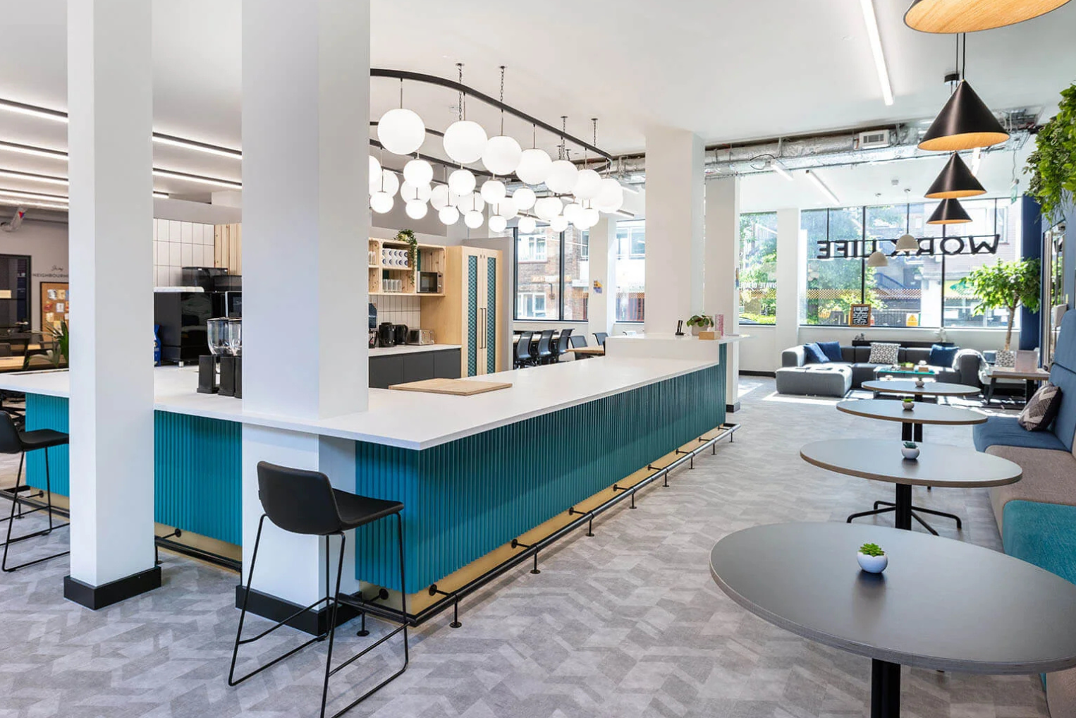 teal fluted kitchen island, globe pendant lighting, and small round cafe tables with a lounge area.