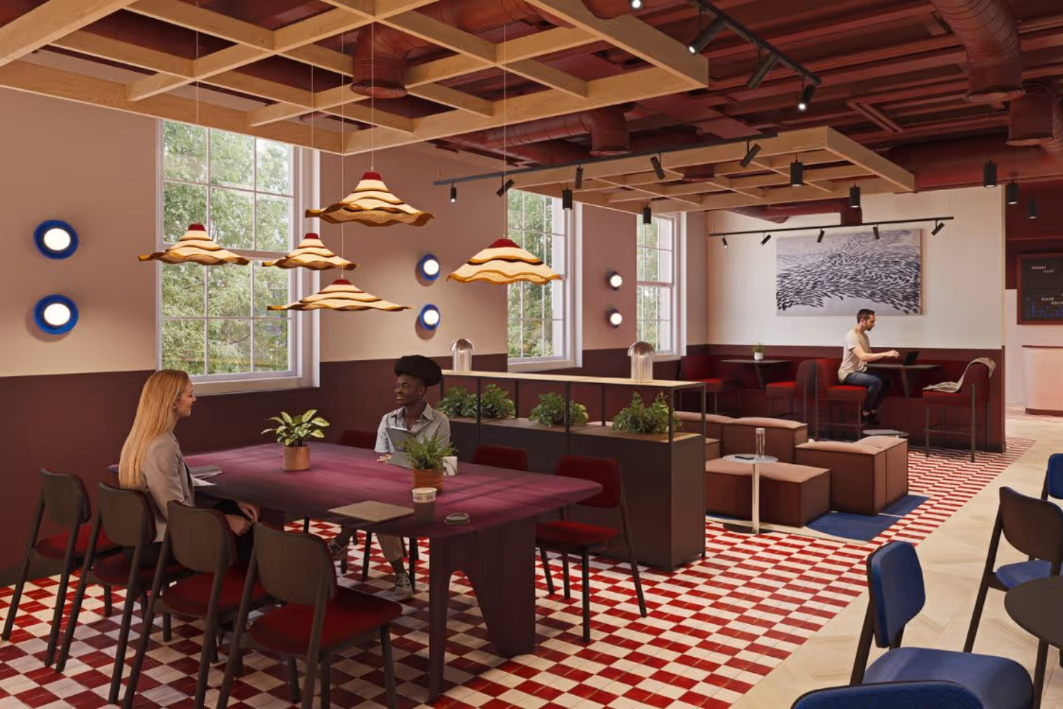 Breakout space with a red and white checkered floor, wave-shaped pendant lights, and people collaborating at a long table.
