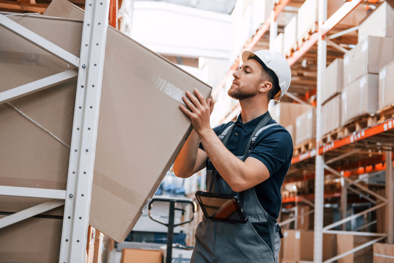 Employee in warehouse is taking out a box from the shelf