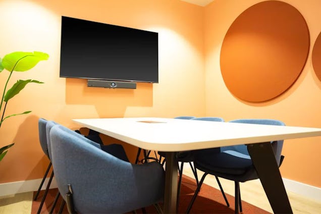 Meeting room with a white table, navy chairs, peach-coloured walls, and circular acoustic panels.