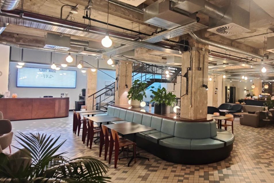 Lounge with a teal banquette and patterned tile floors. There is a pink wooden reception desk with hanging lights dangling from the ceiling.