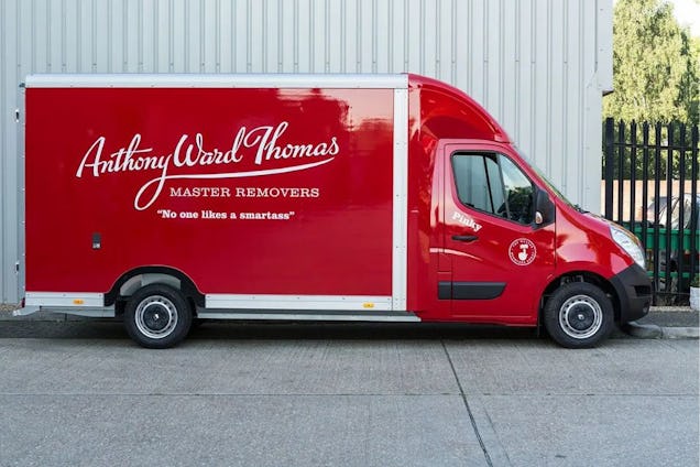 A red and white Anthony Ward Thomas moving van parked on a paved surface.