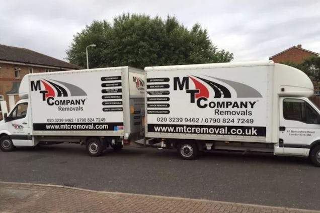 Two white MT Company Removals vans parked on a residential street.