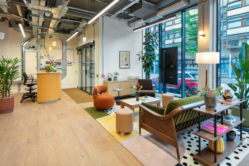 An office reception and lounge featuring a curved wooden desk, mid-century modern furniture, and floor-to-ceiling windows.