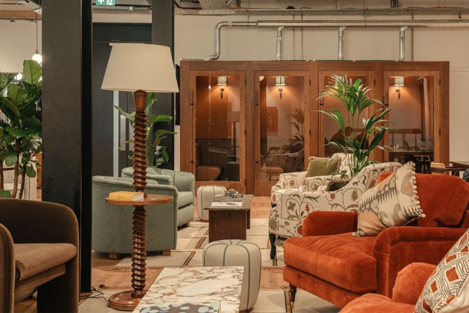 A lounge area with several armchairs and a floor lamp sits in front of wooden phone booths.
