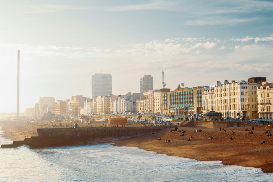 View of Brighton Beach with people sitting on the sand by the sea