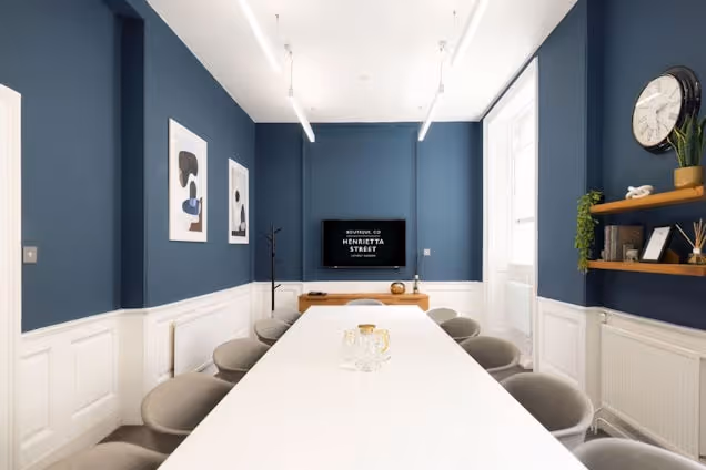 Boardroom with a long white table, grey chairs, navy blue upper walls, and white lower panelled walls.